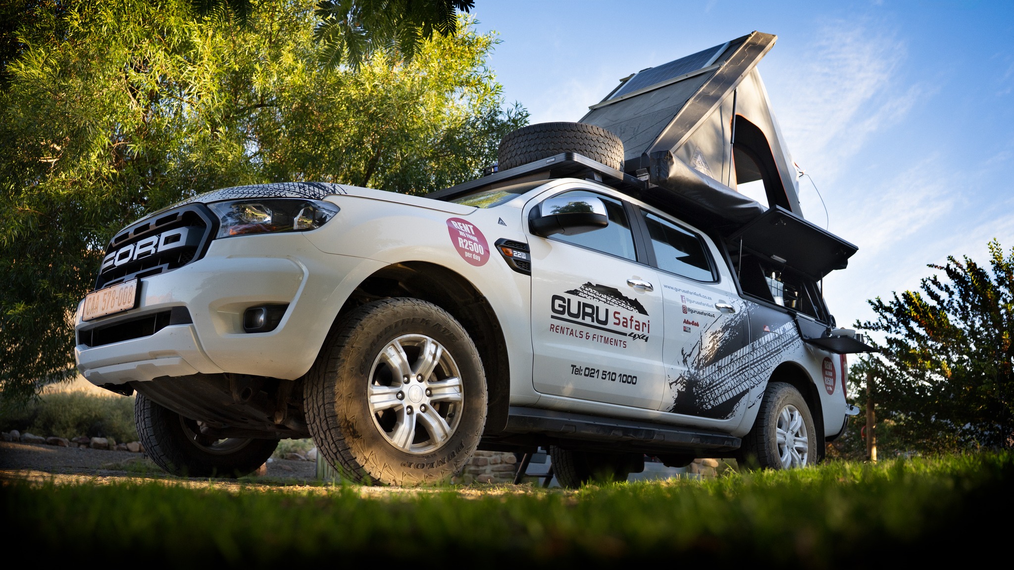 ford ranger 4x4 with an open rooftop tent, spare wheel, and distinctive blackwhite branding, ready for an overland adventure